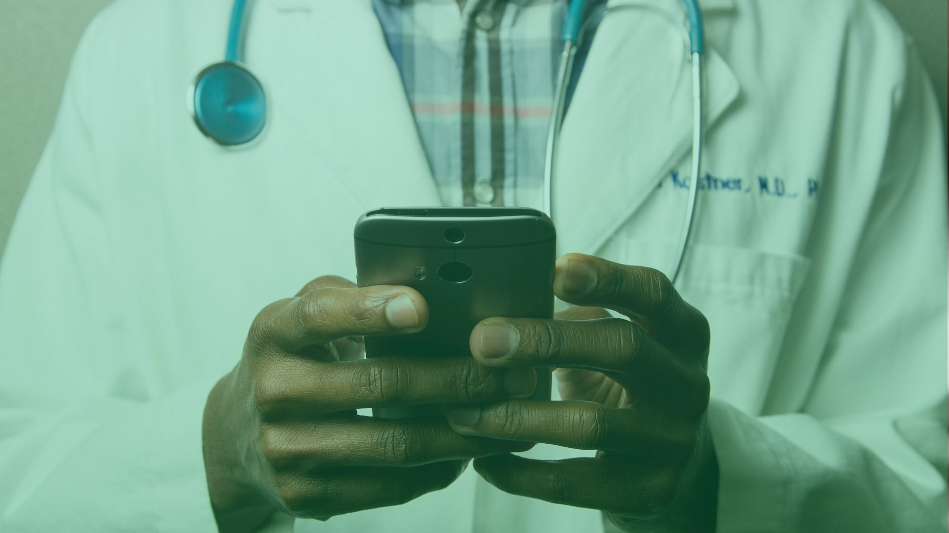 Doctor holding mobile device. Communicating with colleagues, highlighting the importance of intranet compliance for security.